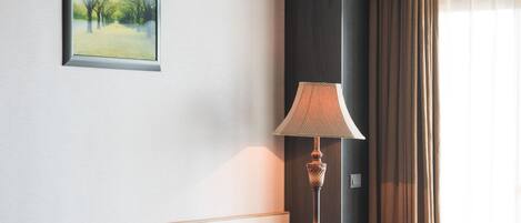 Een hotelkamer met een paarse bank, een bed, een vloerlamp en een schilderij aan de muur.