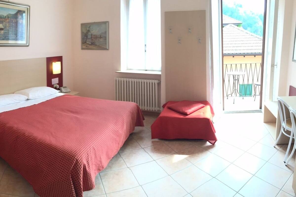 Una habitación de hotel con dos camas, un área de descanso y un balcón.