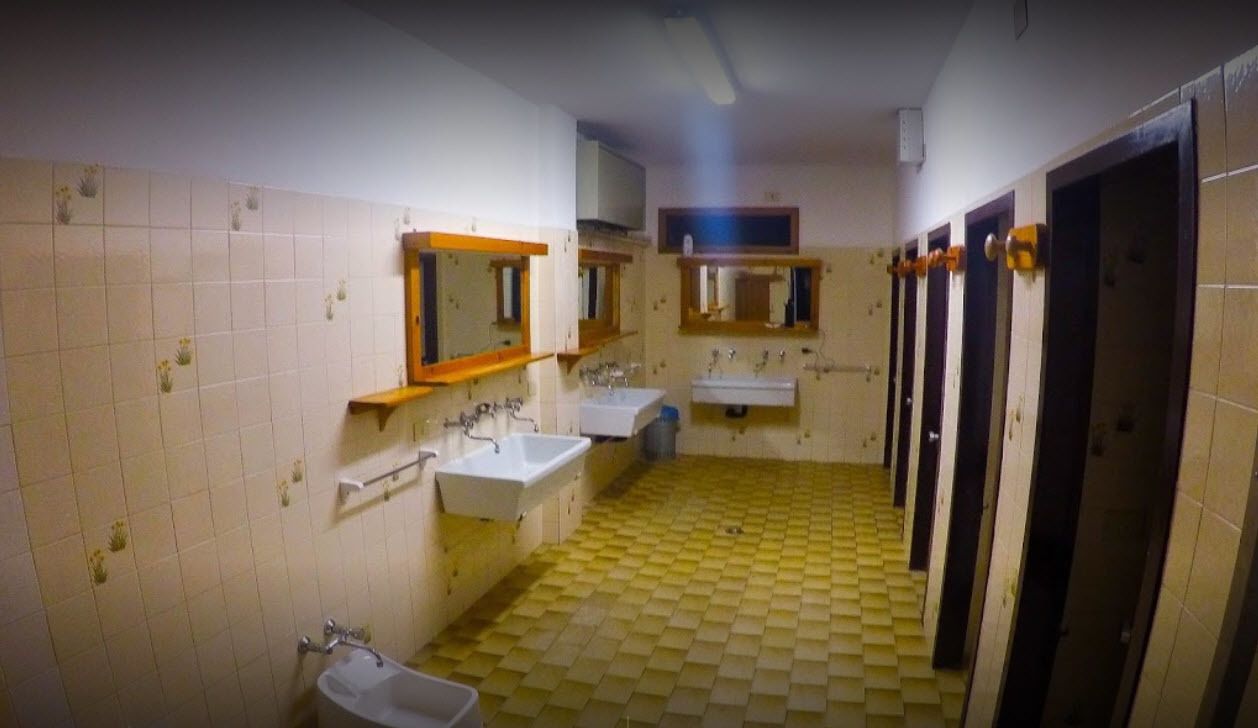 Eine öffentliche Toilette mit zwei Waschbecken, Spiegeln, einer Toilette und einem gefliesten Boden.