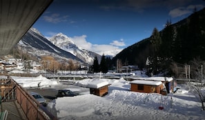 A snowy mountain village with wooden cabins and a view of snow-covered peaks. - Camping Hotel La Pineta (Valdidentro)