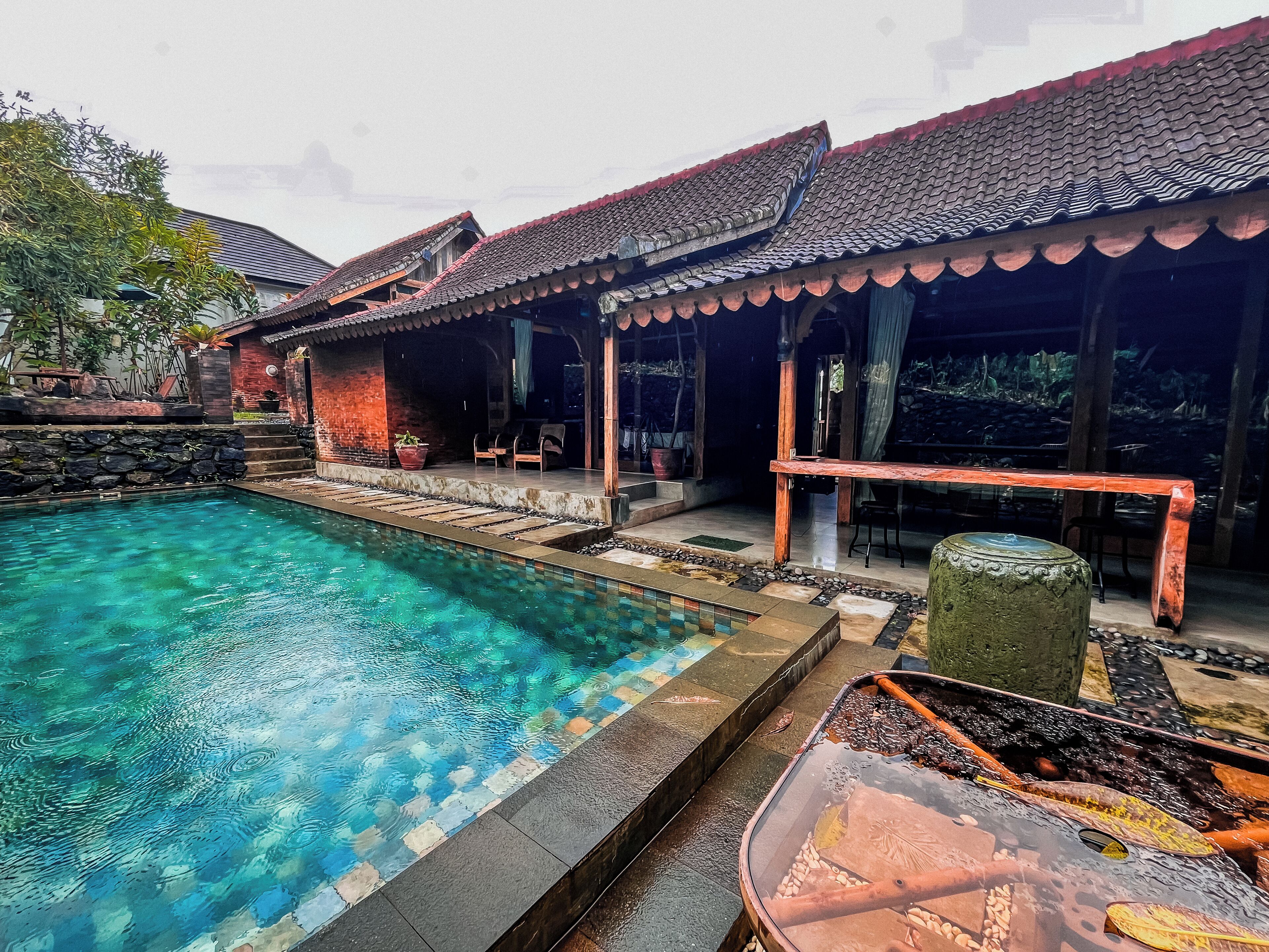 Un edificio tradicional con piscina, escalones de piedra y mobiliario de exterior.