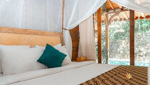 A bed with white linens, a teal pillow, and a woven bedspread.