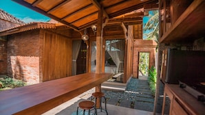 A wooden bar area with stools, a TV, and a view of the outdoors.