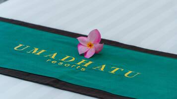 A bed with a green and brown bedspread featuring the text "UMADHATU resorts".