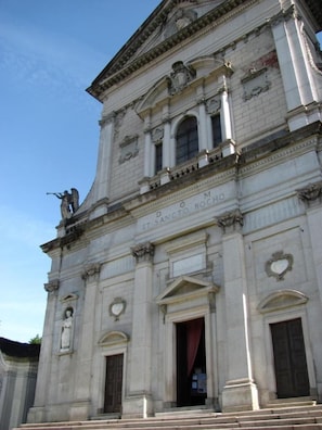 A historic building with classical architecture, featuring a prominent entrance with a red curtain, columns, and statues. - La Genzianella (Miasino)