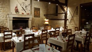 A restaurant with stone walls, wooden tables, and a fireplace. - Auberge du jeu darc (Mello)
