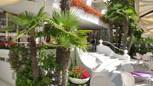 Un jardin sur le toit agrémenté de palmiers, de plantes en pot et d’un espace salon extérieur.