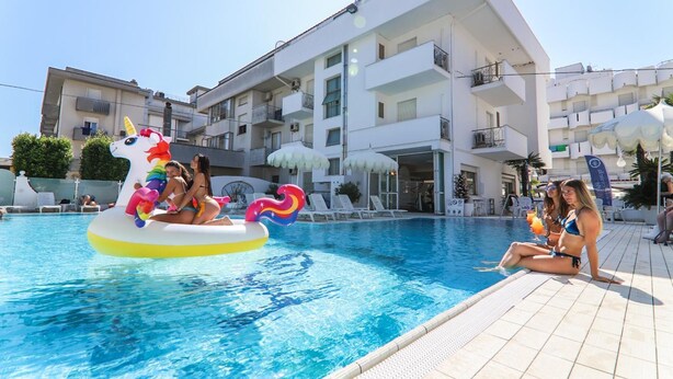 Une piscine avec des bouées en forme de licorne et des chaises longues.