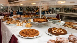 Un buffet proposant une variété de produits de boulangerie et de pâtisserie, présentés sur des assiettes et des présentoirs blancs.