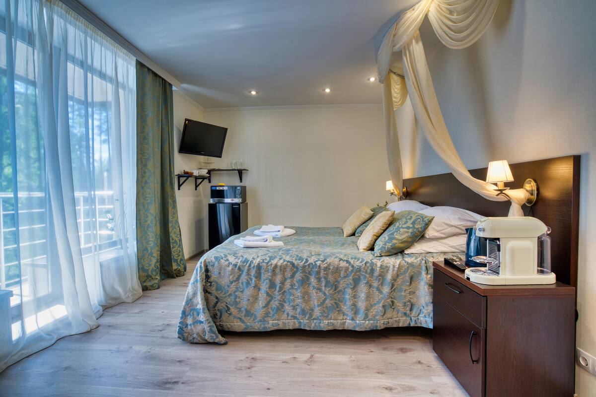 A hotel room with a bed, a TV, a coffee maker, and a nightstand.