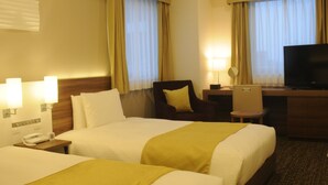 Ein Hotelzimmer mit zwei Betten, einem Schreibtisch, einem Stuhl, einem Fernseher und einem Telefon.