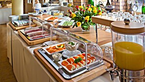 Un montaje tipo buffet con diversos alimentos, una presentación de frutas y un dispensador de zumo.