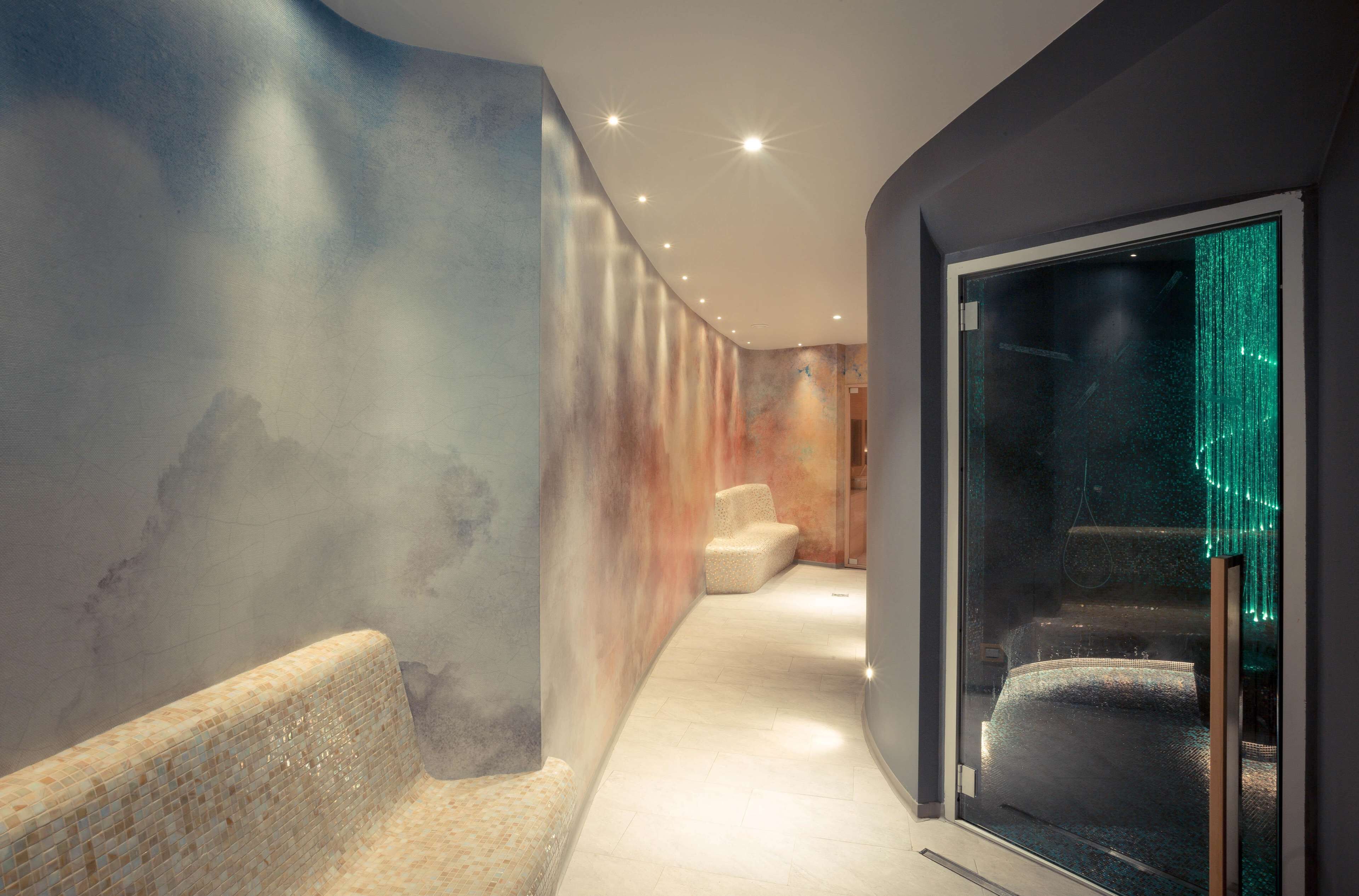 A modern interior with a curved wall, a seating area, and a glass partition with green lighting.