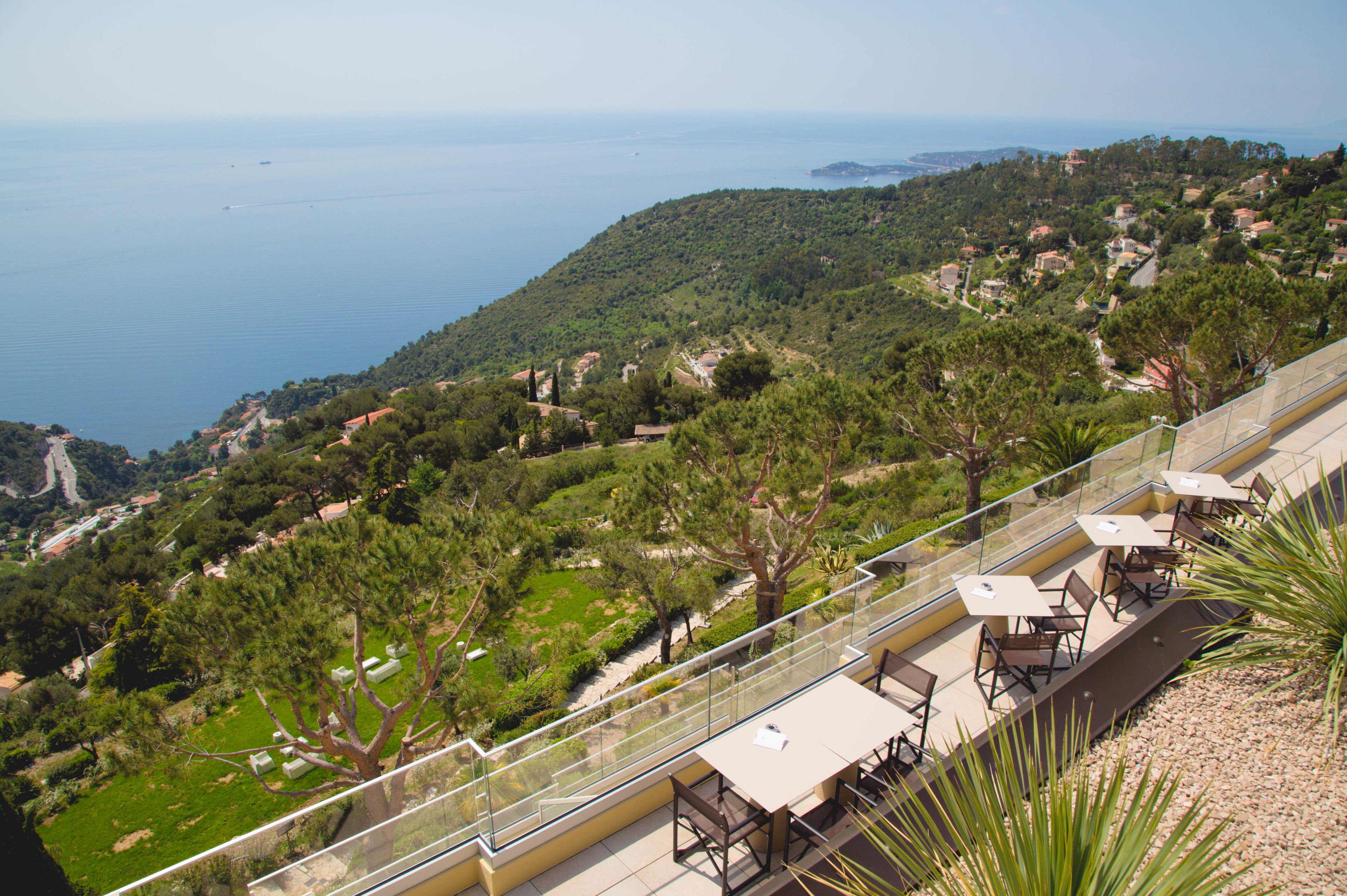 A terrace with outdoor seating overlooking a coastal landscape.