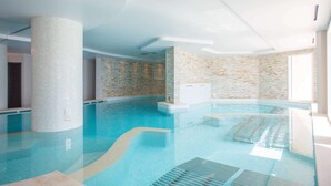 An indoor swimming pool with clear water, tiled walls, and a modern ceiling design. - Hôtel Les Terrasses D'Eze (Èze)