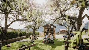 Un parque infantil con una casita de madera, bancos y una zona de césped.