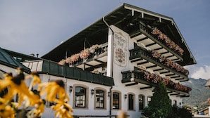 Un edificio tradicional con un techo pronunciado, balcones con jardineras y un cartel llamativo.