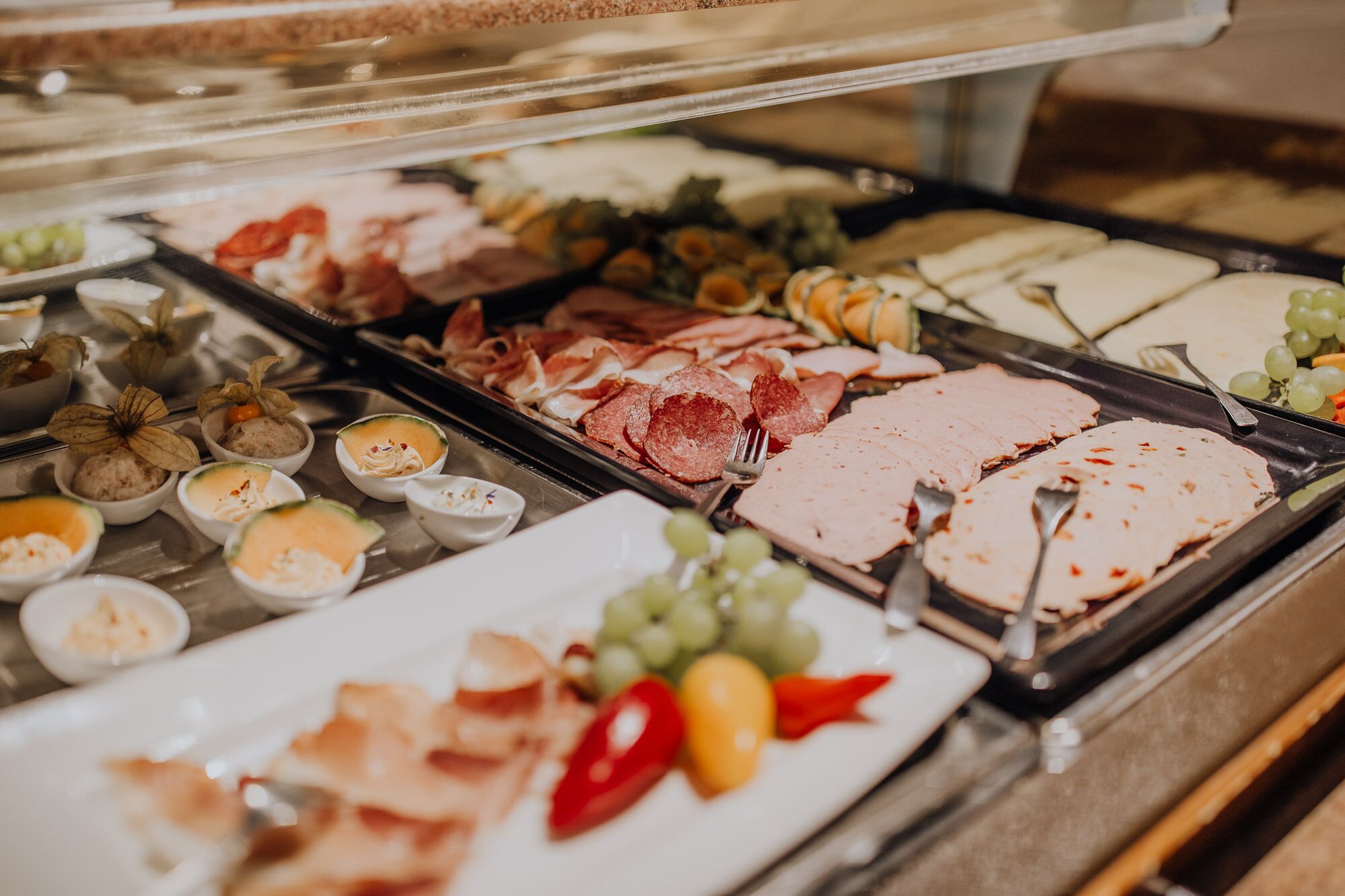 A buffet with various food items including meats, cheeses, and fruits.