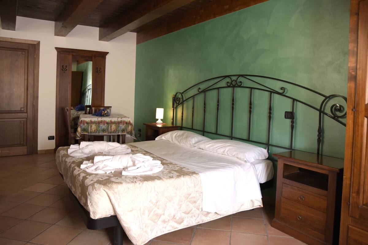 A bedroom with a bed, a dresser, a nightstand, and a mirror.