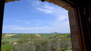 A view through an arched window of a rural landscape with rolling hills, fields, and scattered trees. - L'Oasi di Pierino (Ponzano di Fermo)