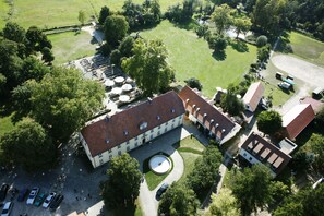 An aerial view of a hotel with a courtyard, parking area, and surrounding greenery.