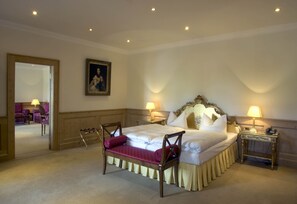 A hotel room with a large bed, two bedside tables with lamps, a chair, a mirror, and a painting on the wall. - Schloss Diedersdorf (Grossbeeren)