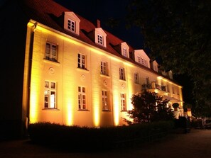 A large, well-lit building with multiple windows and a red roof. - Schloss Diedersdorf (Grossbeeren)