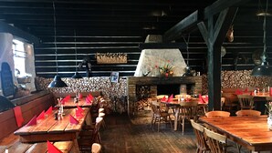 A rustic restaurant interior with wooden tables and benches, a stone wall, and a fireplace. - Schloss Diedersdorf (Grossbeeren)
