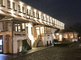 Um edifício histórico com uma escadaria que leva à entrada, uma placa e uma rua de paralelepípedos.