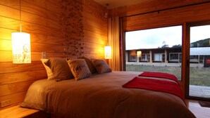 Una habitación de madera con una cama, almohadas y una ventana.