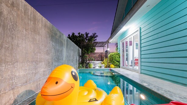 Piscina con un grande anatroccolo gonfiabile, uno scivolo e un muro in cemento.