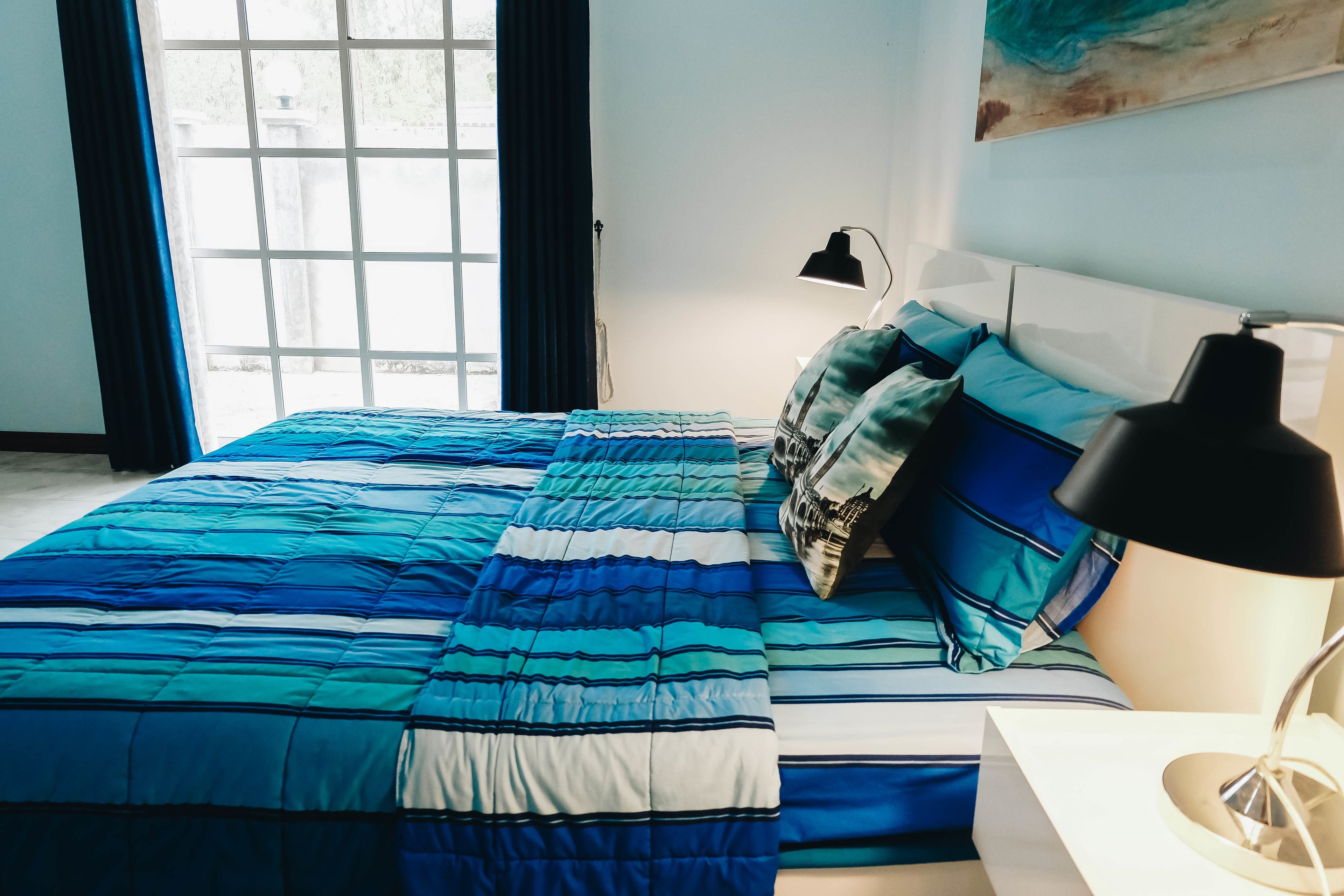 A bedroom with a bed, a bedside lamp, and a window with curtains.