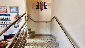 Un escalier avec des rampes en métal, menant à un palier où sont accrochés un tableau et un certificat.