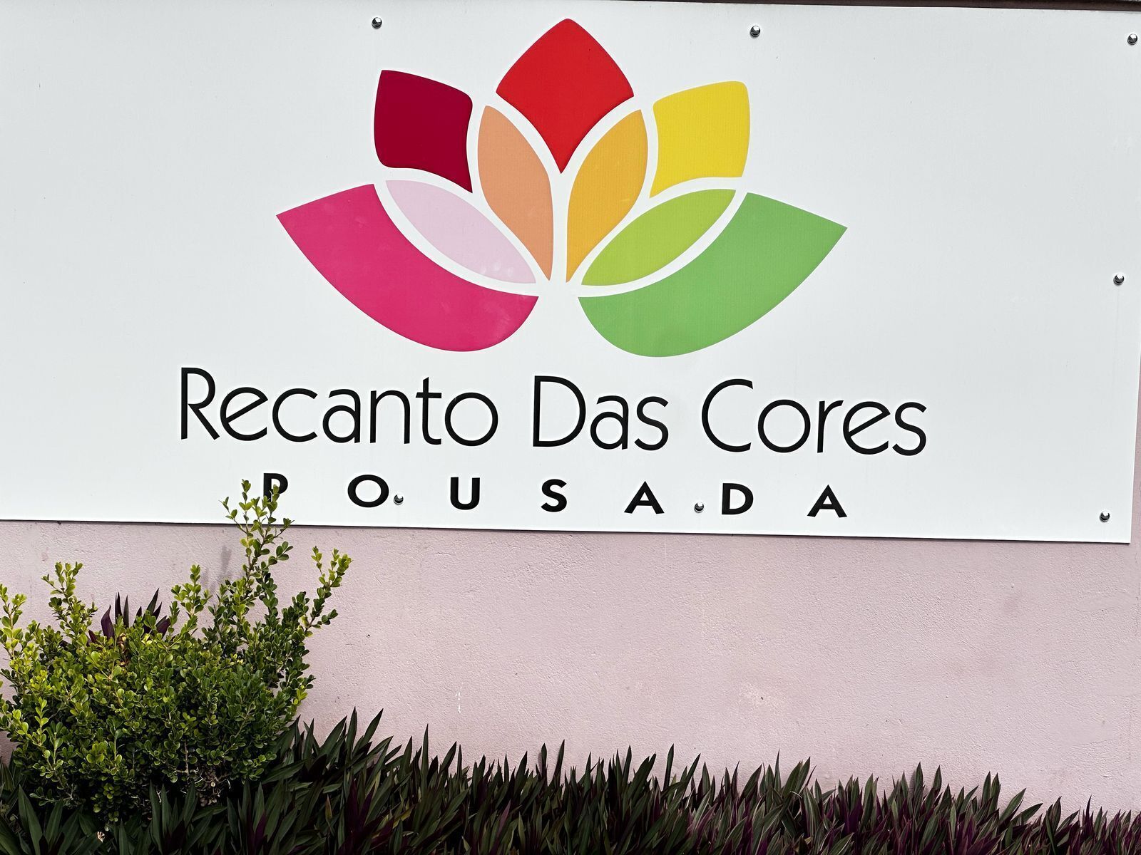 A sign for Recanto Das Cores with a colorful logo and the name 'P.O.U.S.A.D.A' below it.