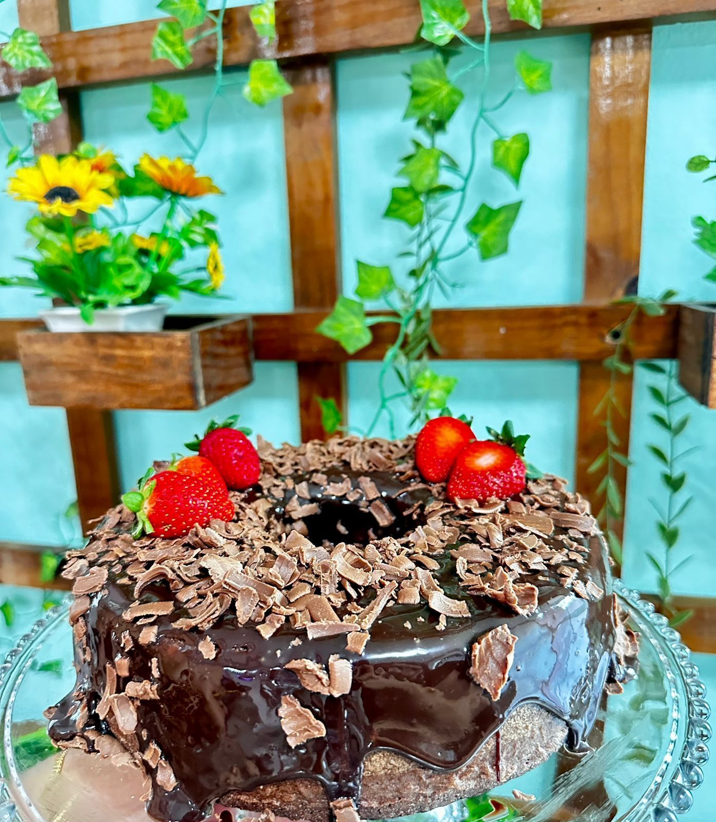 A chocolate cake with strawberries on a glass stand.