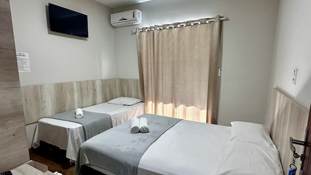 Une chambre d’hôtel avec deux lits, une télévision, un système de climatisation et un plancher en bois.