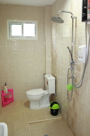 Une petite salle de bain avec des toilettes, une douche et une fenêtre.