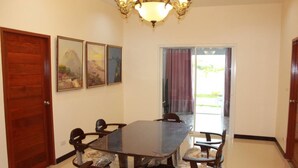 A dining room with a rectangular table, six chairs, a chandelier, and two doors. - Pitchayapa Hua Hin Pool Villa Holiday (Hua Hin)
