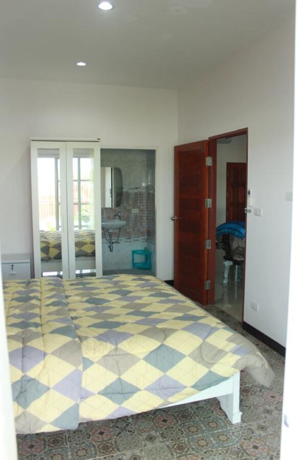 Une chambre à coucher comprenant un lit, une armoire, une salle de bain et une porte donnant sur une autre pièce.