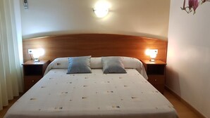 A hotel room with a large bed, two bedside tables, and a wall-mounted light fixture. - Hostal Mary (Lloret de Mar)