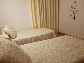 Un dormitorio con dos camas, un cojín, una lámpara y un adorno en la pared.