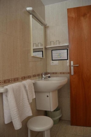 Un baño con lavabo, espejo e inodoro.