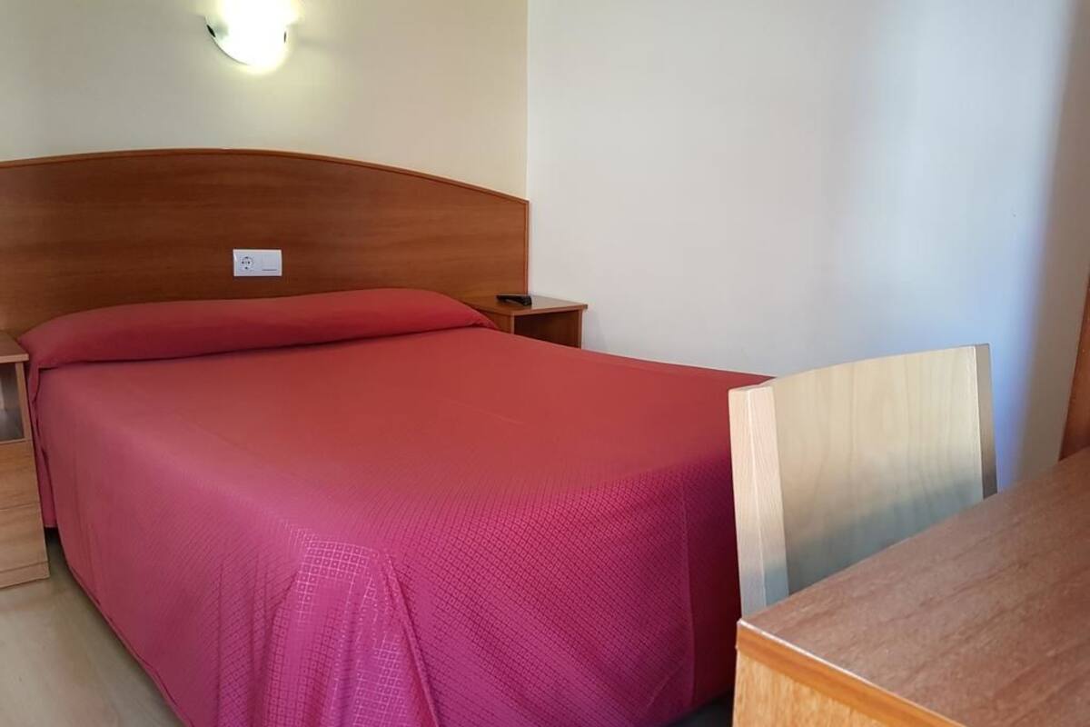 A single bed with a wooden headboard, a nightstand, and a bedside table.