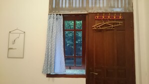 Ein Zimmer mit Holztür, einem Fenster mit Blick auf Grünflächen, einem Pendelschalter und einem Wäscheständer.