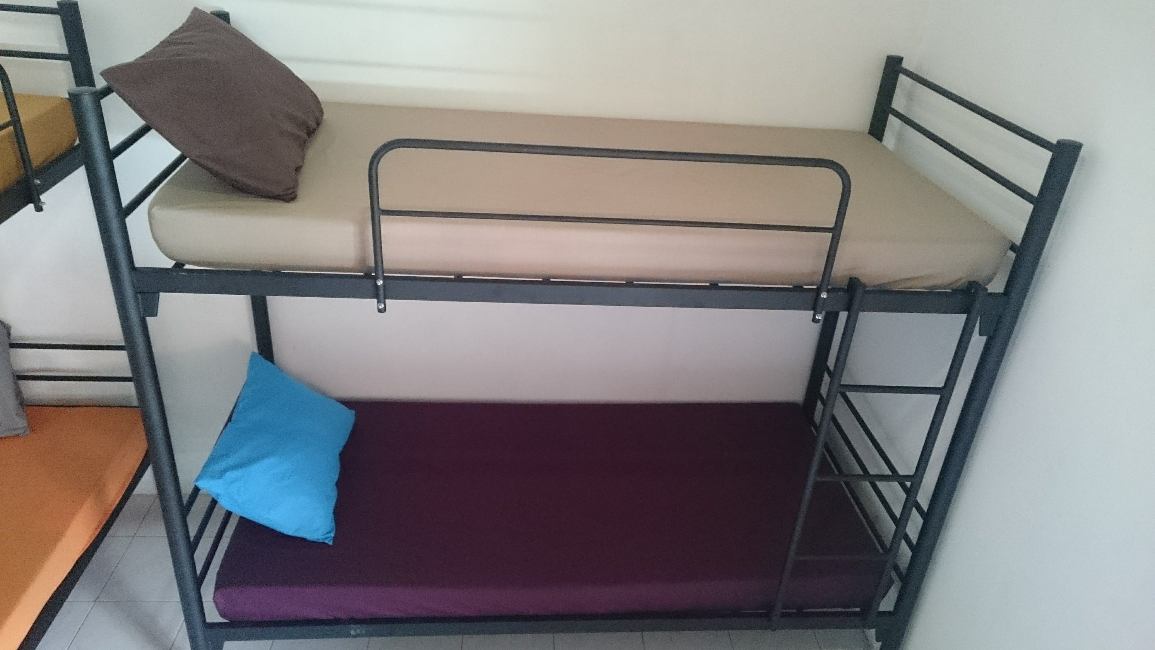 Un lit superposé à deux niveaux, avec un oreiller marron sur le lit du haut et un oreiller bleu sur le lit du bas.