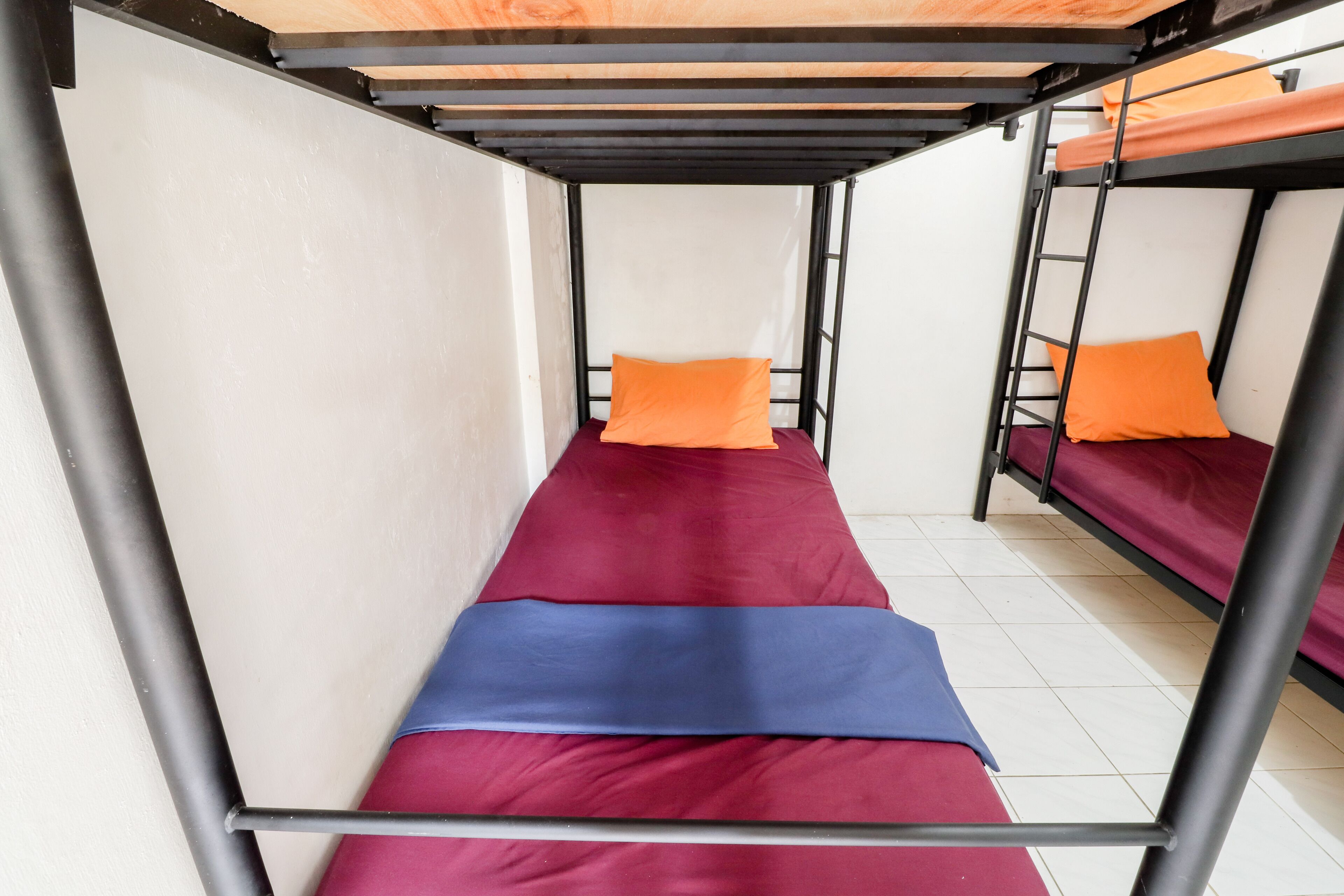 Une chambre avec un lit superposé, comportant deux lits, chacun avec un oreiller orange.