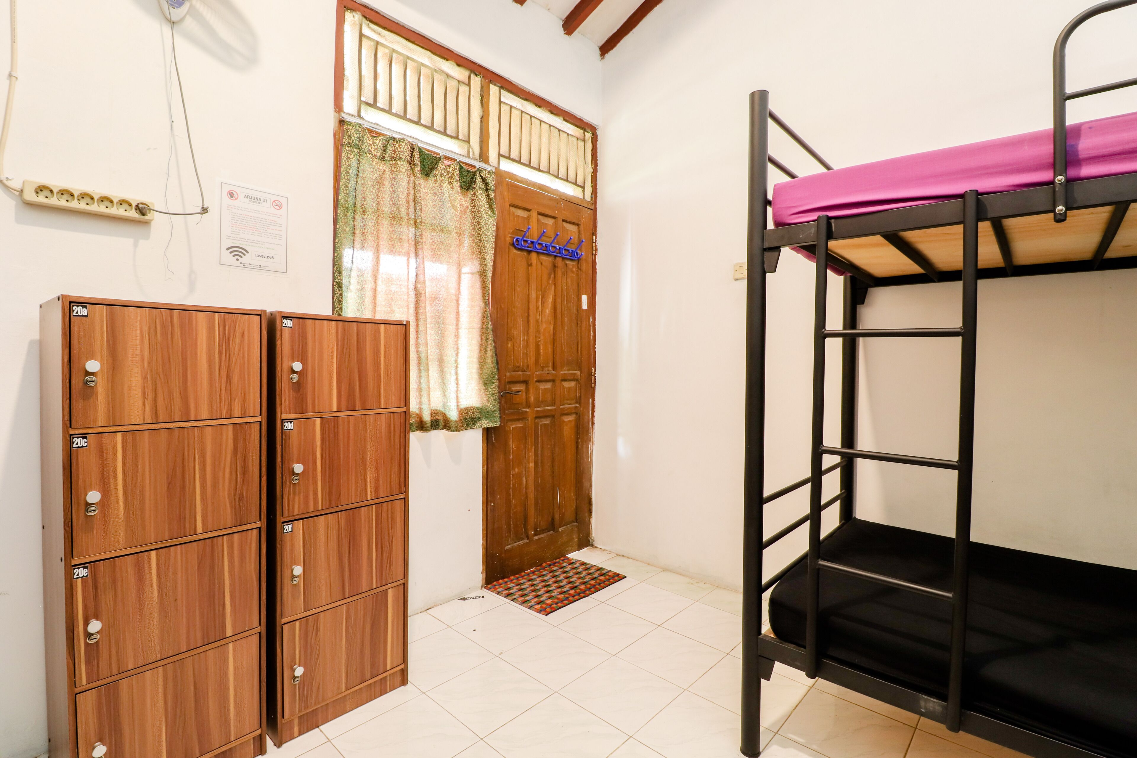 Una habitación con literas, armarios de madera, una puerta con ventanal y suelo de baldosas.