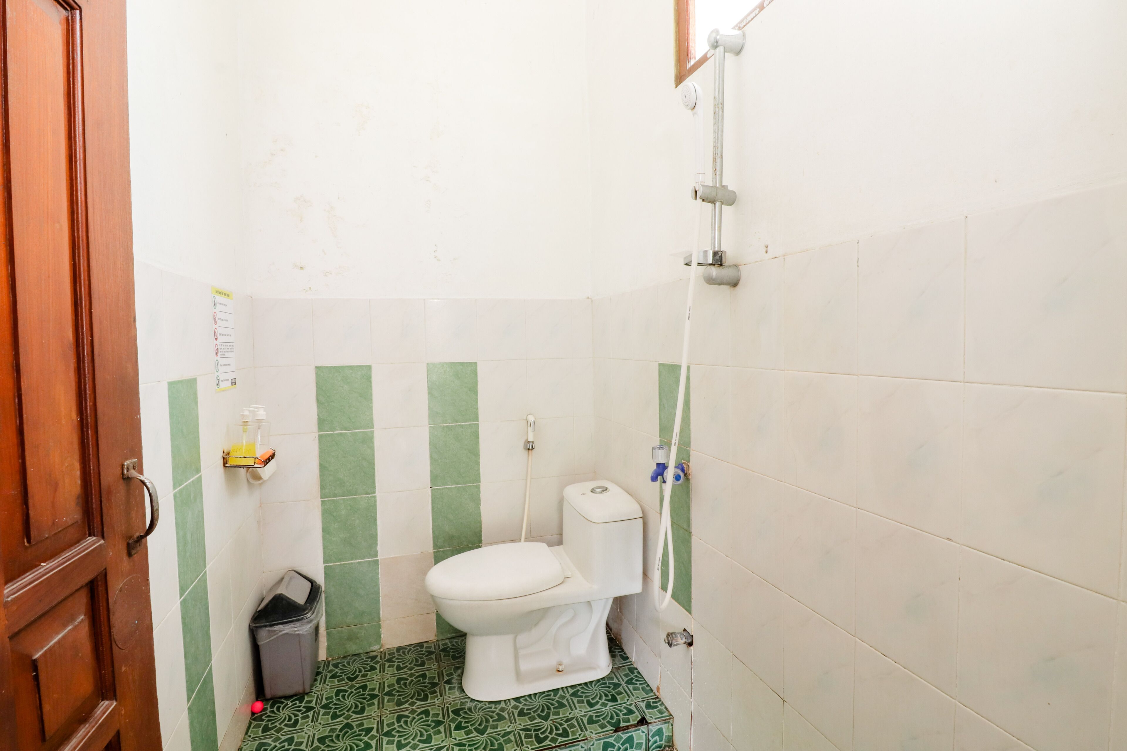 Un baño pequeño con inodoro, un cubo de basura y ducha.