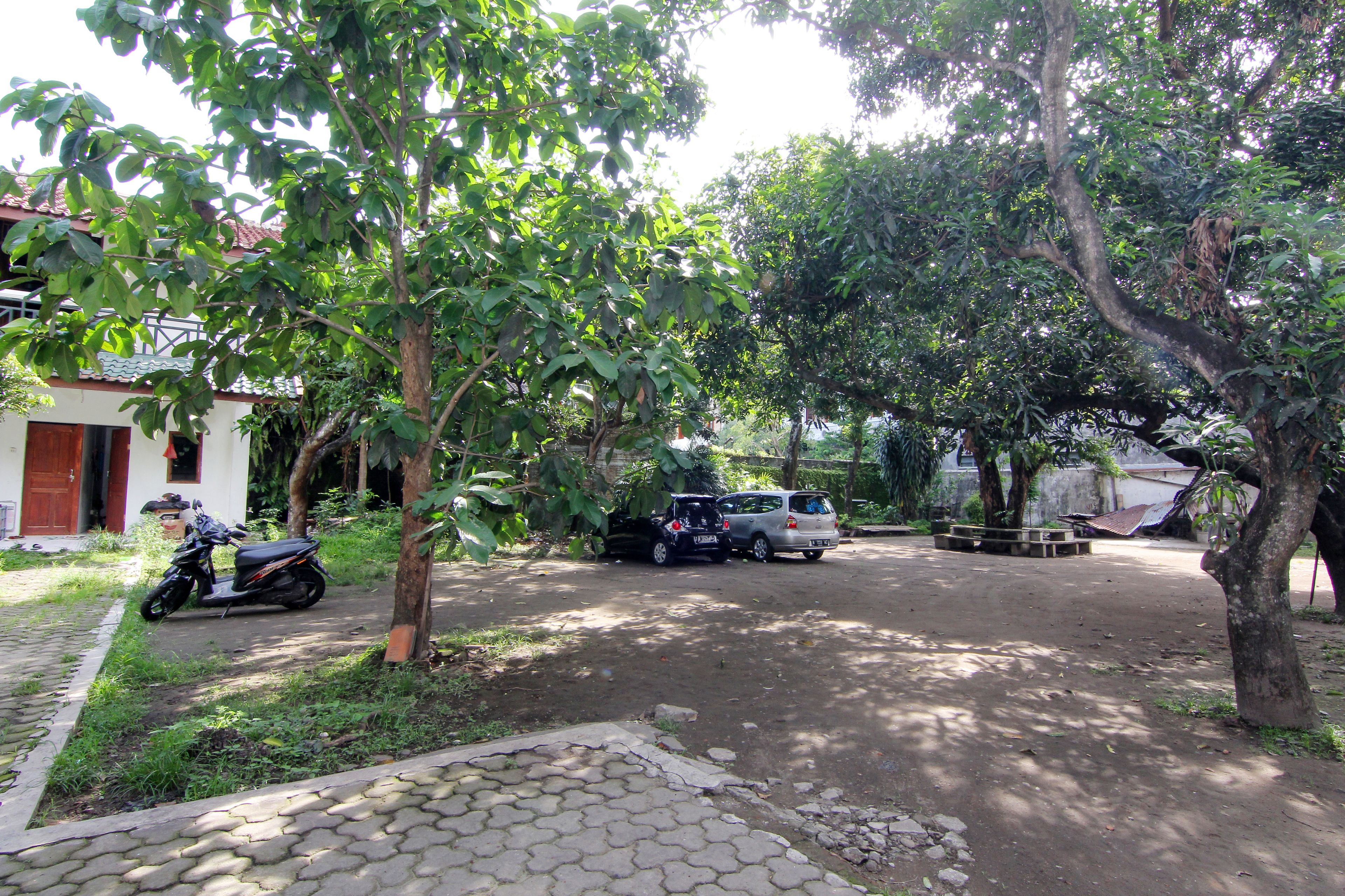 A paved driveway with a parked motorcycle and two cars.