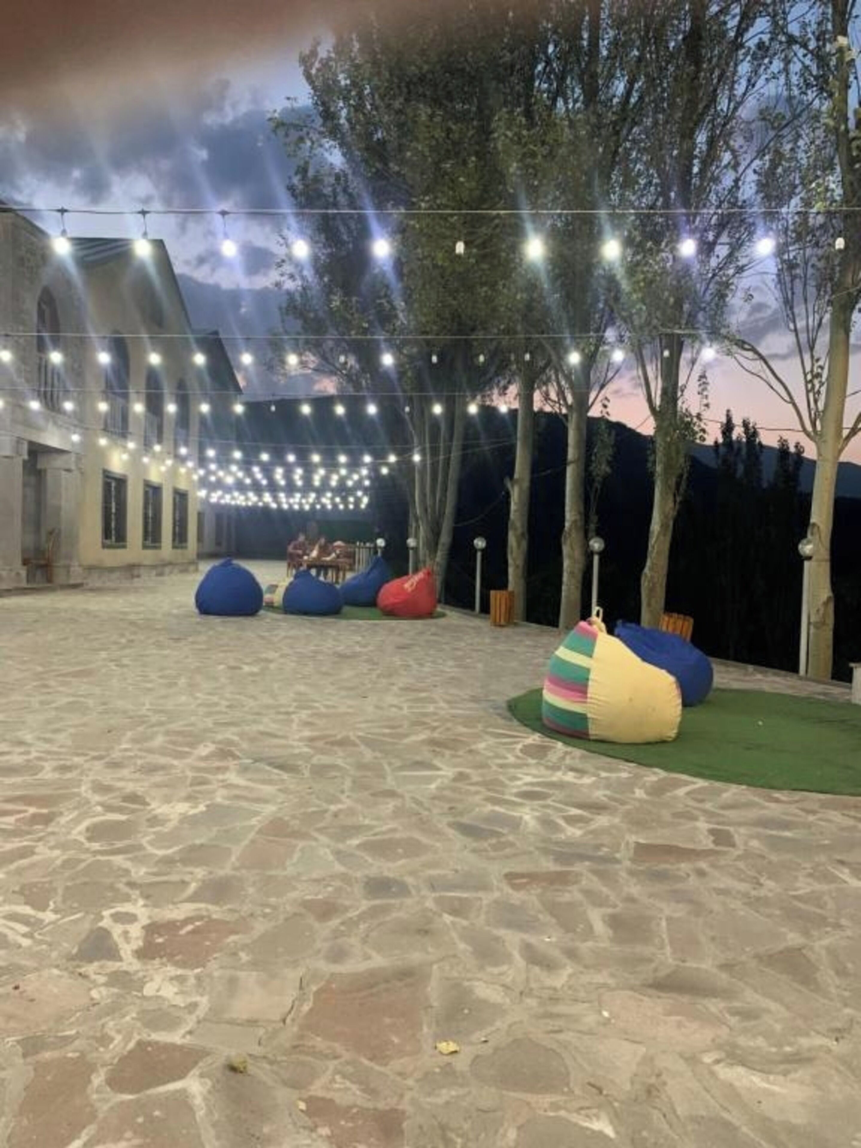 Un espacio al aire libre con piso de piedra, luces colgantes y sillones de tumba divertidos.